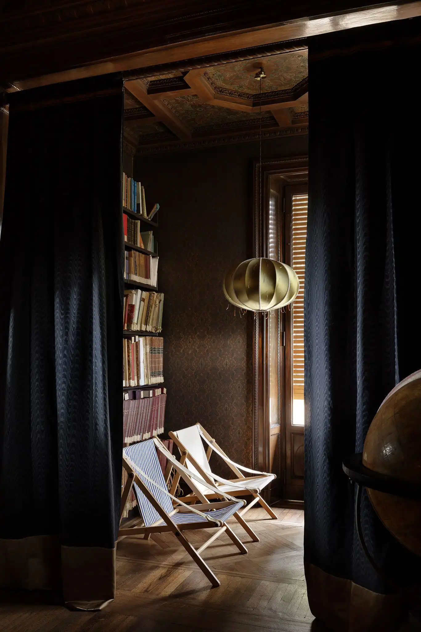Allestimento della biblioteca con sdraio da esterno e lampada custom in seta e vetro di Murano