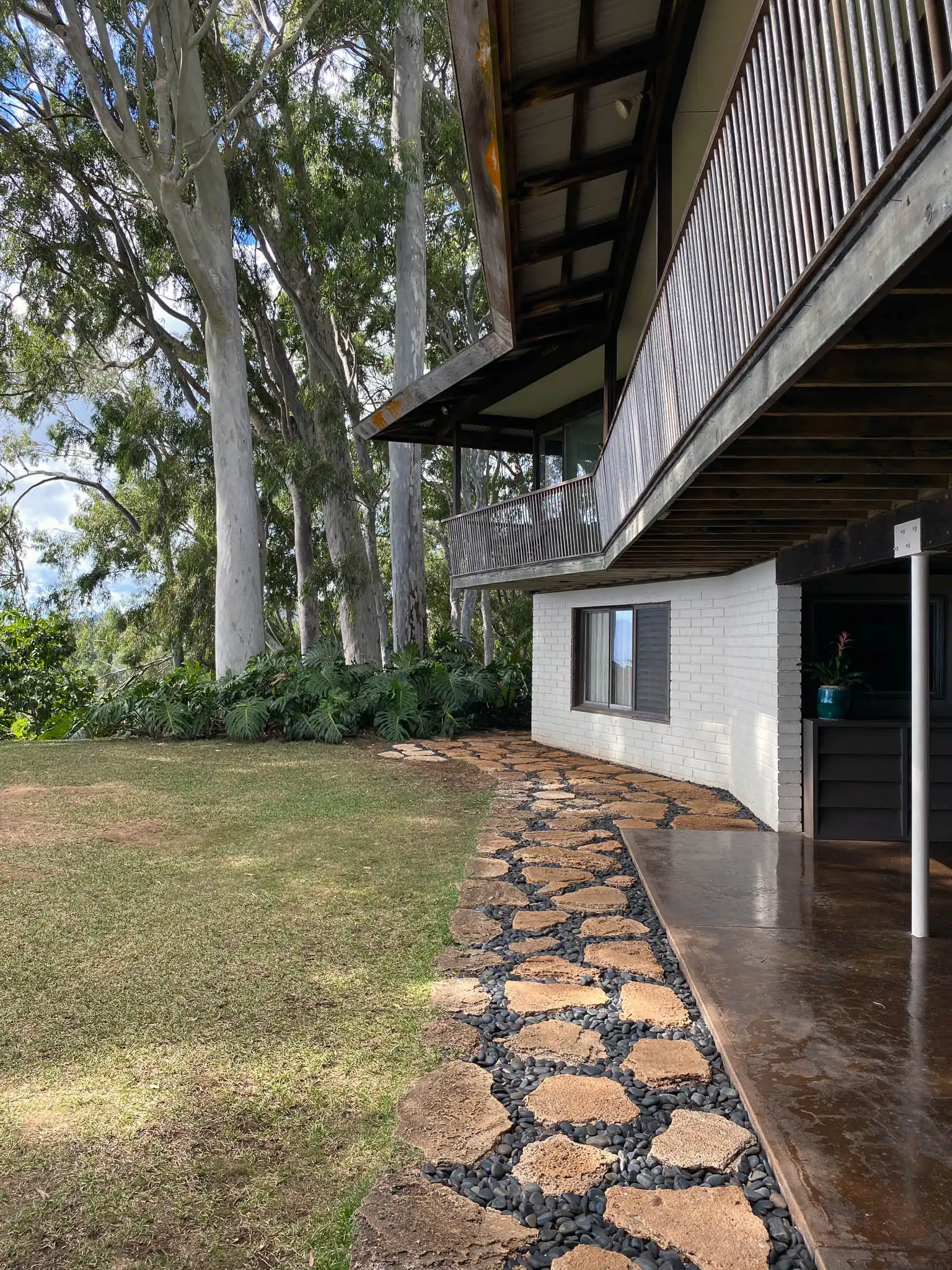 Vista esterna architettonica casa nella foresta di Honolulu con camminamento perimetrale in pietra