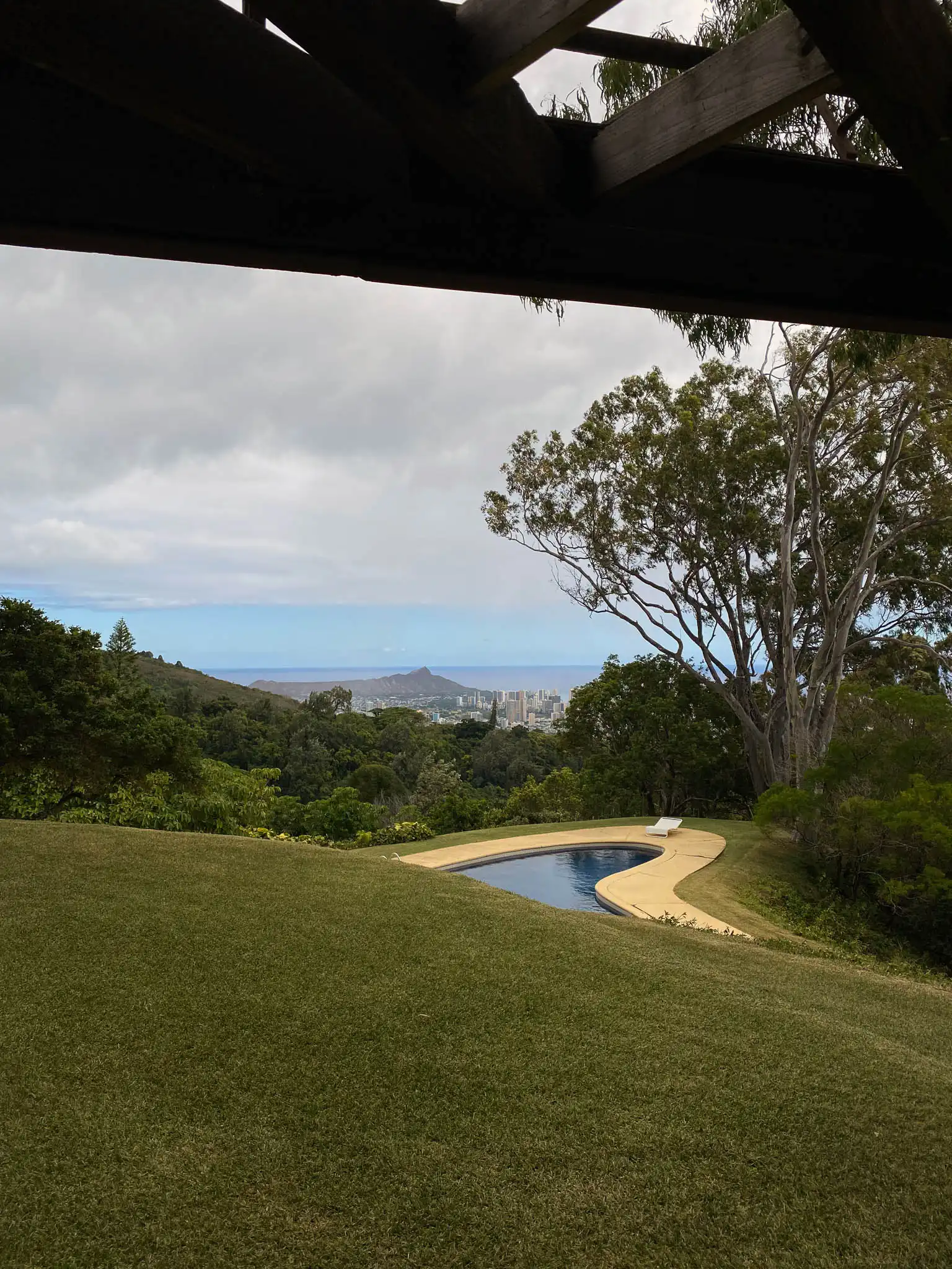 Vista esterna architettonica casa nella foresta di Honolulu con piscina ovaloide modernista e vista sulla baia