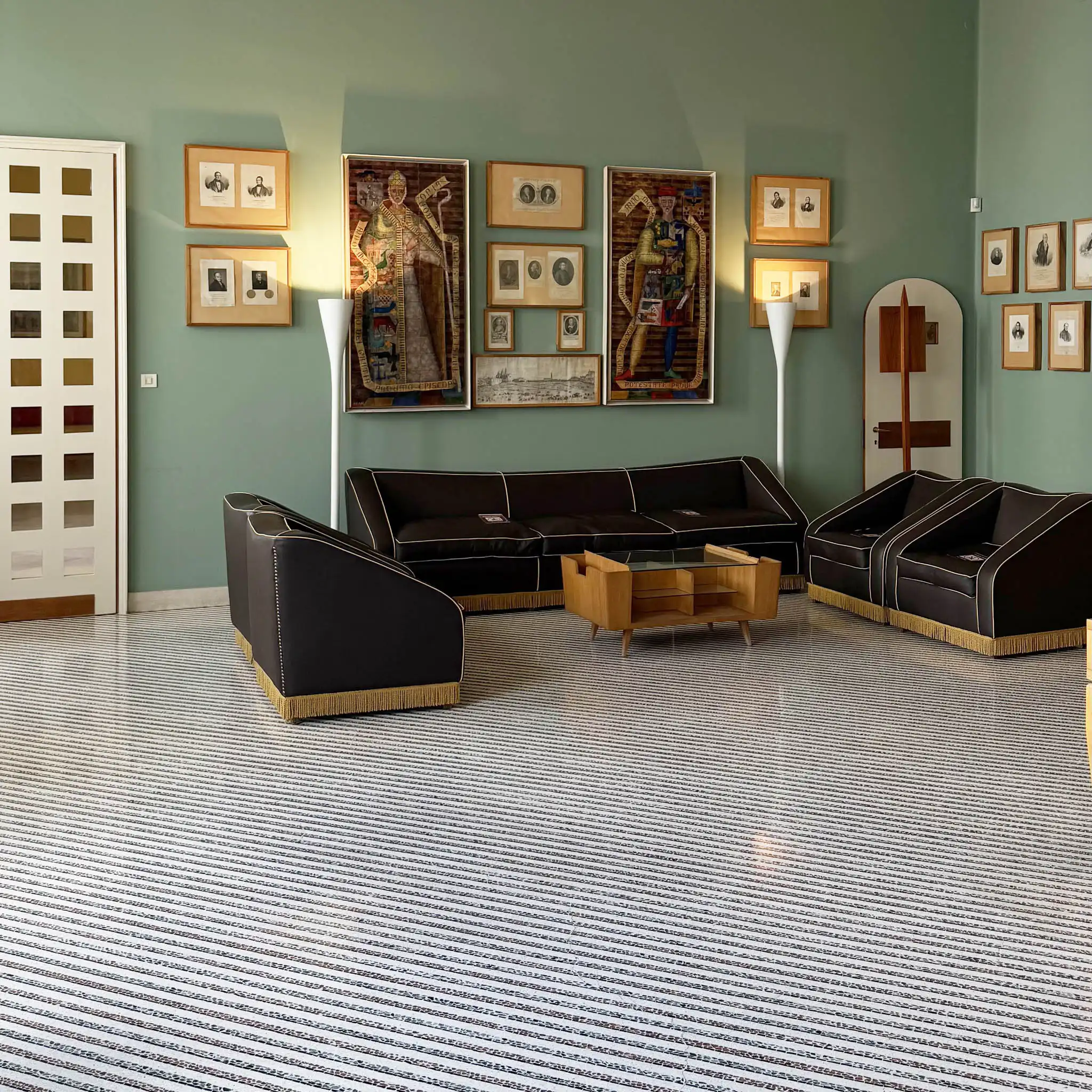 Vista open space con famiglia di divani neri con dettaglio ottone e arte