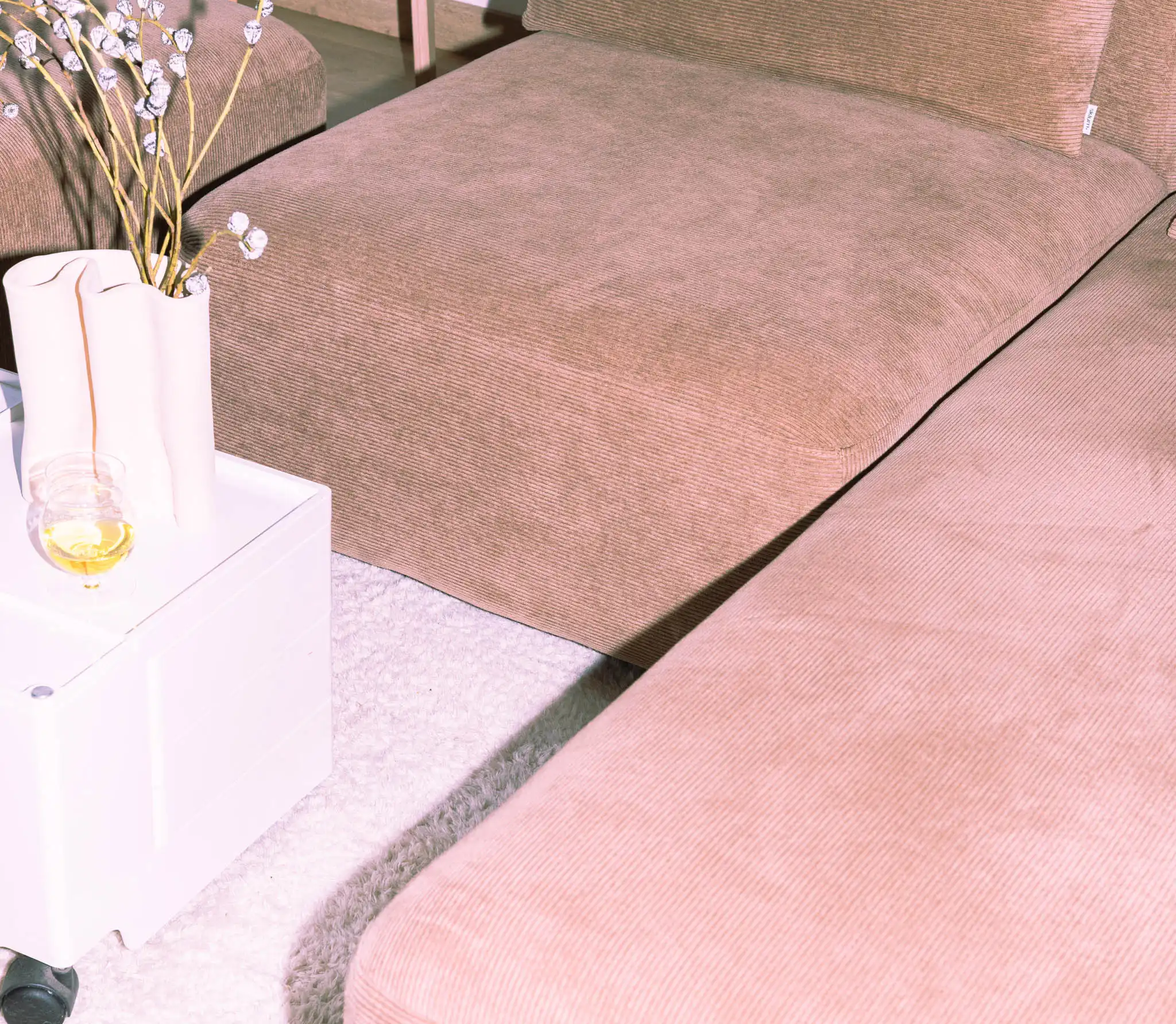 Divano in velluto marrone con coffee table Bob bianco e vaso ceramico; sullo sfondo sgabello nordico in betulla.