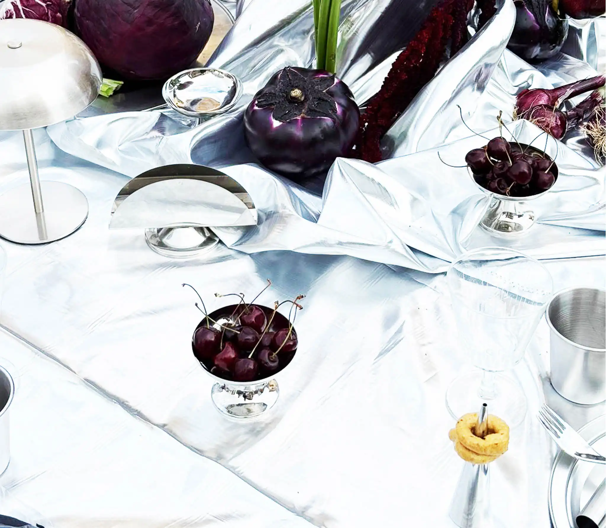 Dettaglio di decorazione da tavola con inserti metallici e frutta rossa.