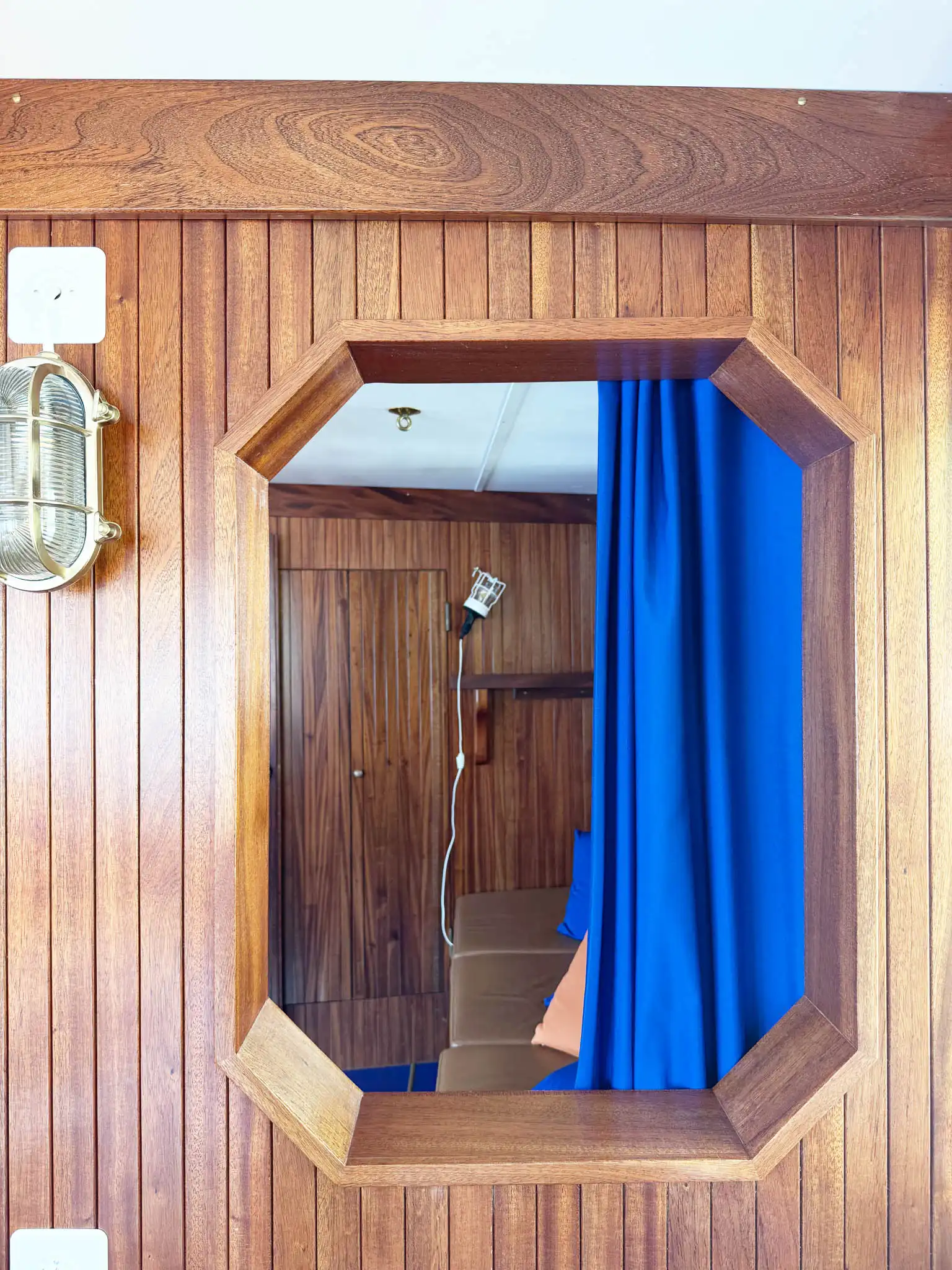 Dettaglio architettonico interno con finestra rivestita in legno cannettato e tenda blu