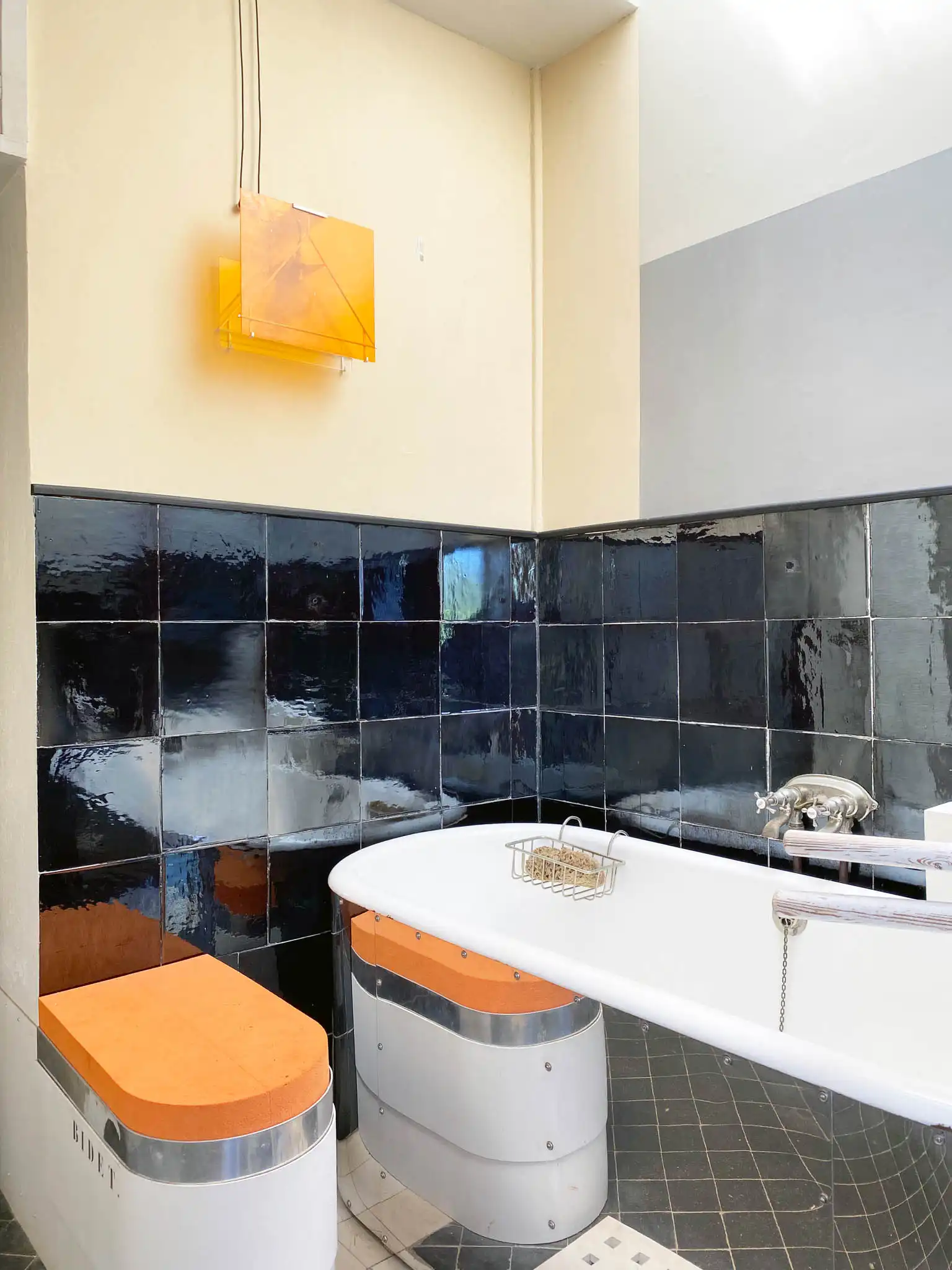 Bagno con piastrelle nere e elementi modernisti arancio